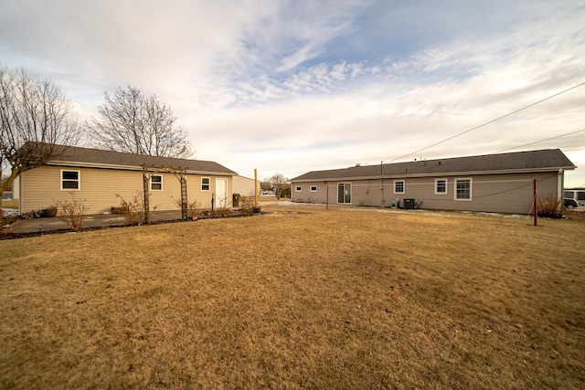 back of property with a yard and central AC