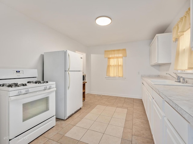 kitchen featuring white cabinetry, sink, light tile patterned floors, and white appliances