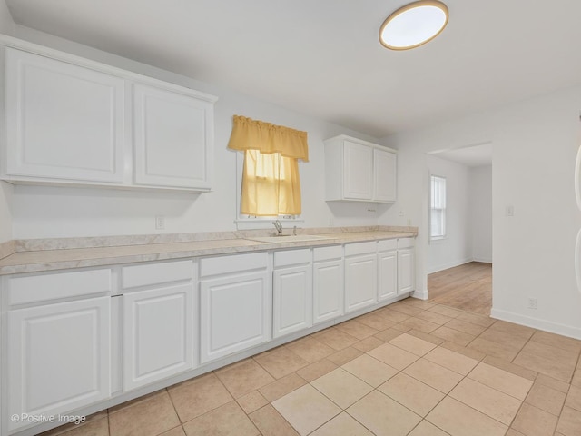 kitchen featuring white cabinetry, sink, and light tile patterned flooring