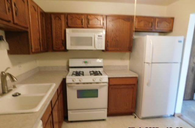 kitchen featuring white appliances and sink