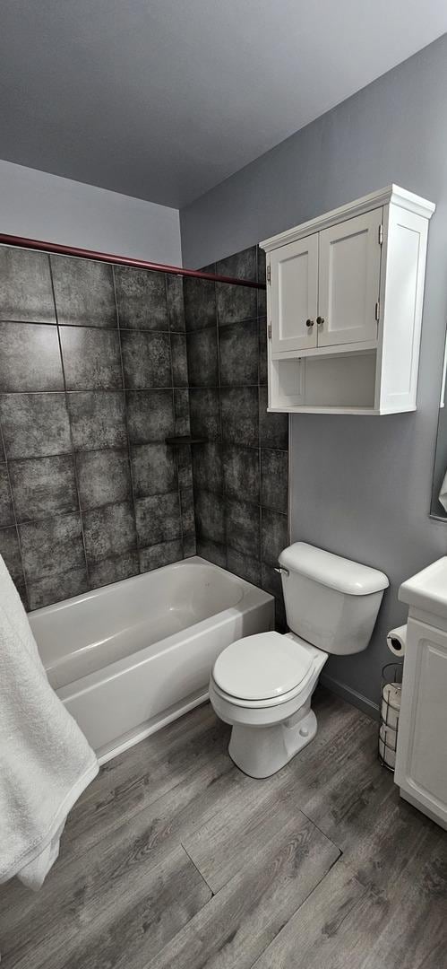 bathroom with vanity, wood finished floors, baseboards, bathtub / shower combination, and toilet