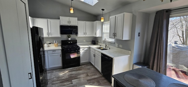 kitchen with black appliances, light countertops, wood finished floors, white cabinetry, and a sink