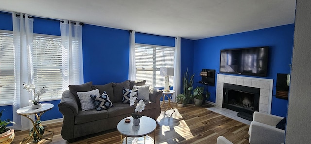 living area with wood finished floors, baseboards, and a tile fireplace