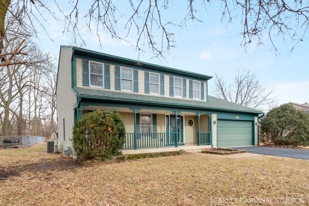 view of front of property with central AC, a porch, a garage, and a front lawn