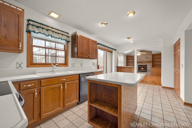 kitchen with light tile patterned flooring, built in features, a fireplace, dishwasher, and sink