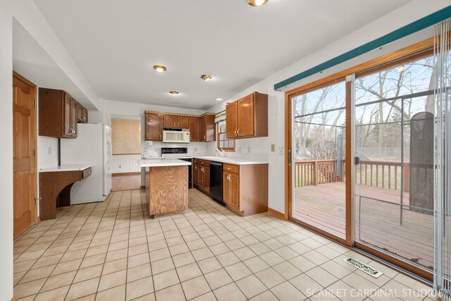 kitchen with white appliances, a kitchen bar, a kitchen island, and light tile patterned floors