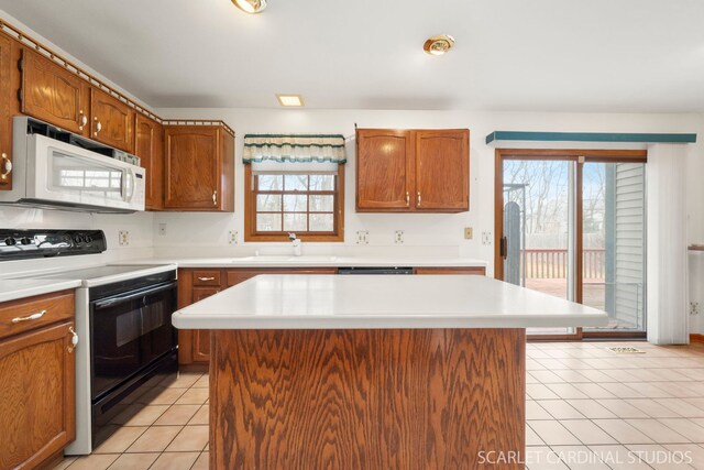 kitchen featuring dishwashing machine, sink, a kitchen island, light tile patterned flooring, and black range with electric cooktop