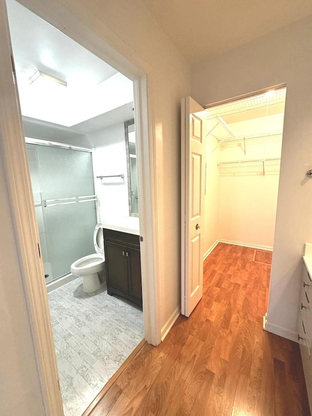 bathroom with hardwood / wood-style flooring, vanity, an enclosed shower, and toilet