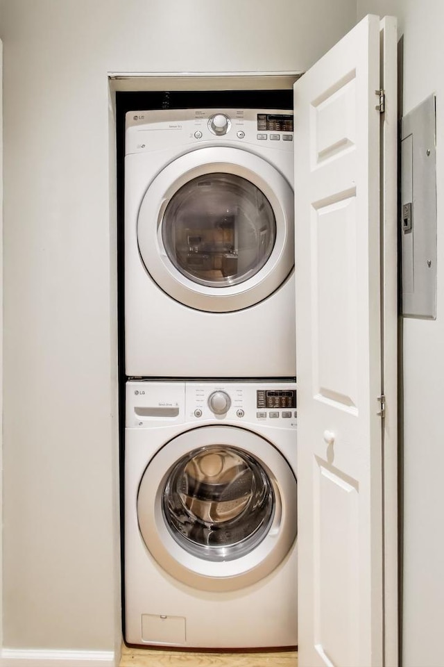 clothes washing area with stacked washer / drying machine and electric panel