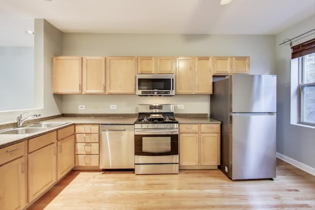 kitchen with light brown cabinetry, sink, light wood-type flooring, and appliances with stainless steel finishes