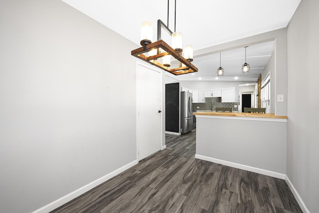 kitchen featuring pendant lighting, wood counters, tasteful backsplash, white cabinets, and stainless steel fridge