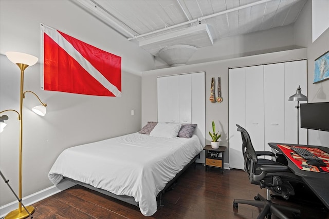 bedroom with two closets and dark hardwood / wood-style flooring