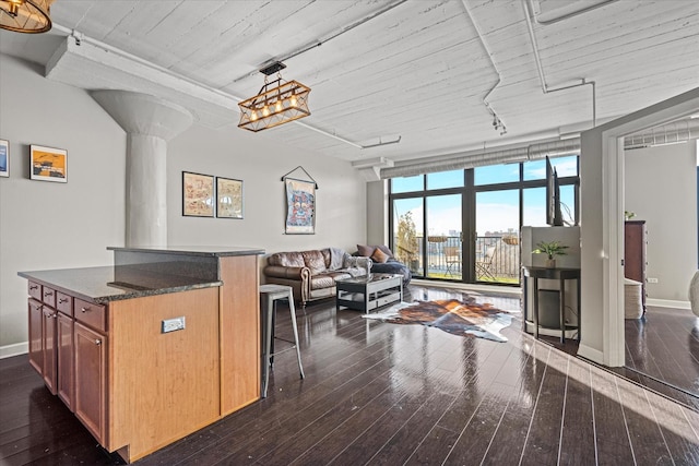 kitchen with dark wood-type flooring, a breakfast bar, dark stone countertops, a center island, and expansive windows