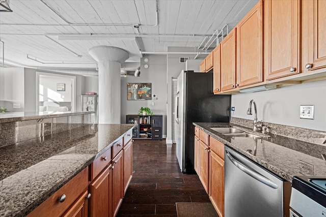 kitchen featuring appliances with stainless steel finishes, sink, dark hardwood / wood-style floors, and dark stone counters