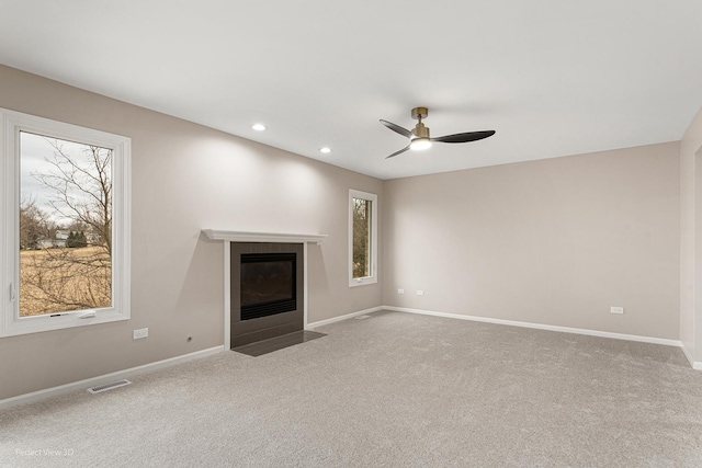 unfurnished living room with ceiling fan, light colored carpet, and a fireplace