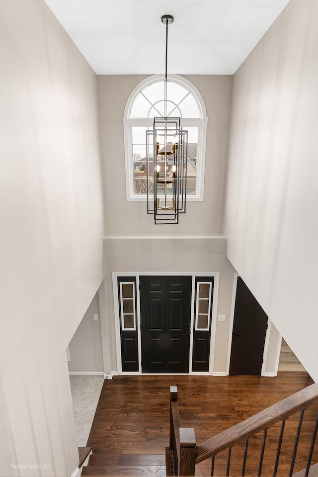 foyer entrance featuring a high ceiling, wood-type flooring, and a notable chandelier