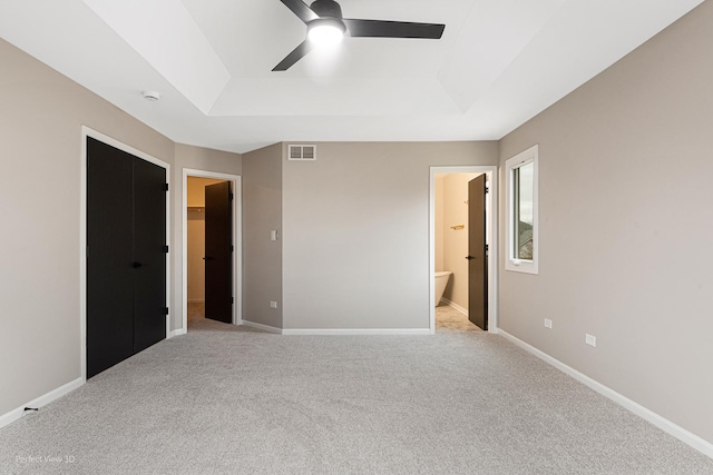 unfurnished bedroom featuring light colored carpet, a spacious closet, and a raised ceiling