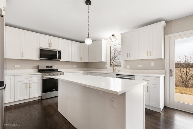 kitchen with a center island, dark hardwood / wood-style floors, pendant lighting, stainless steel appliances, and white cabinets