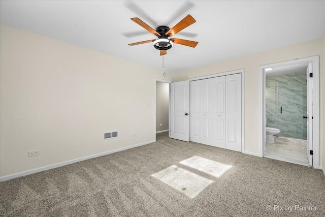 unfurnished bedroom featuring ensuite bathroom, carpet, ceiling fan, and a closet