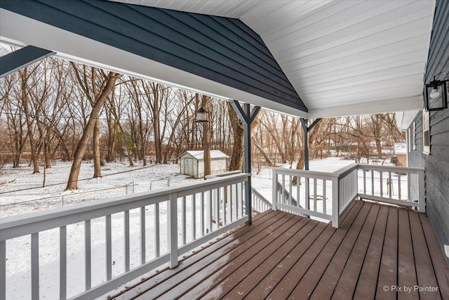 snow covered deck featuring a storage shed