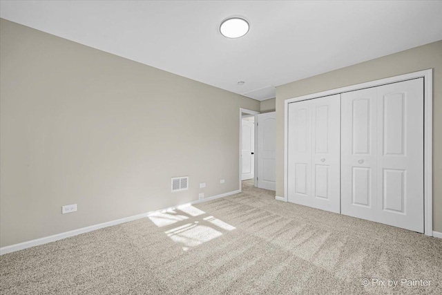 unfurnished bedroom with light carpet and a closet