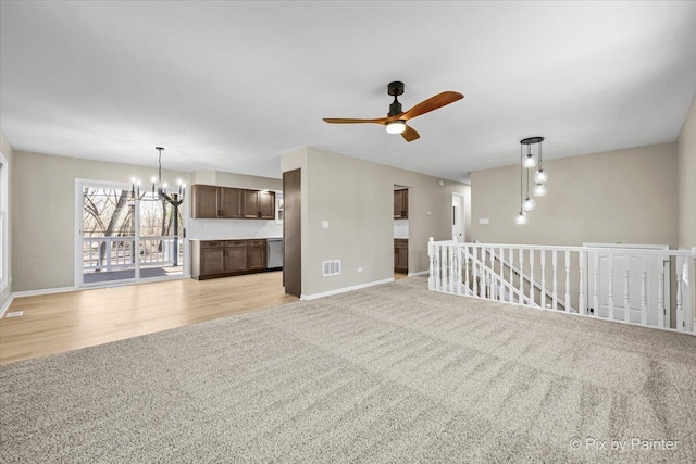 unfurnished living room featuring light colored carpet and ceiling fan with notable chandelier