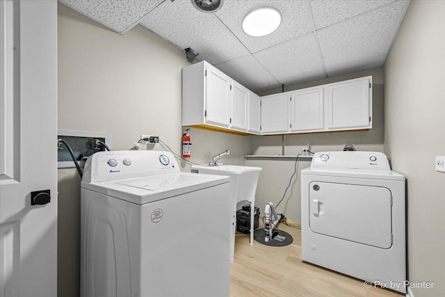 washroom featuring cabinets, washing machine and clothes dryer, and light wood-type flooring