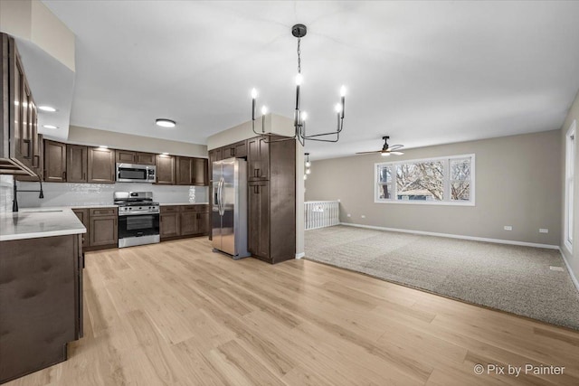 kitchen with appliances with stainless steel finishes, sink, dark brown cabinets, and light hardwood / wood-style flooring