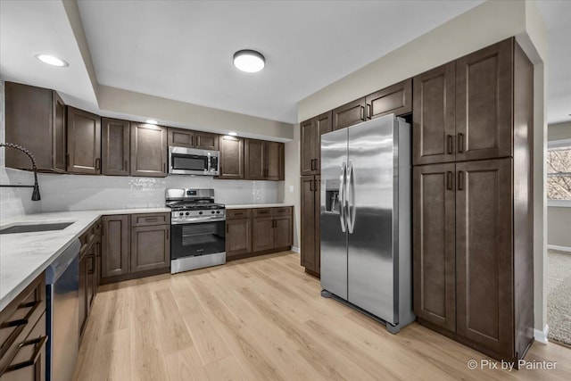 kitchen with sink, decorative backsplash, light hardwood / wood-style floors, stainless steel appliances, and dark brown cabinets