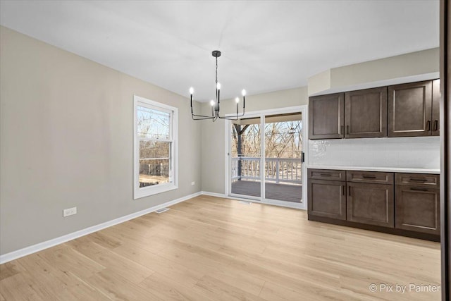 unfurnished dining area featuring light hardwood / wood-style floors, a chandelier, and a healthy amount of sunlight