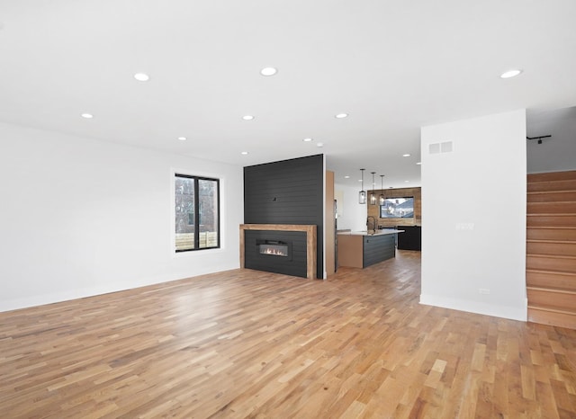 unfurnished living room with sink, a fireplace, and light hardwood / wood-style floors