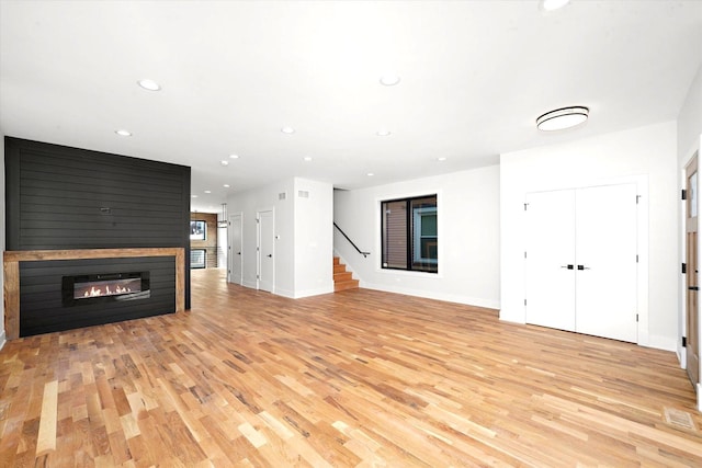 unfurnished living room featuring light hardwood / wood-style floors and a large fireplace