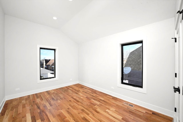 empty room featuring vaulted ceiling and light wood-type flooring