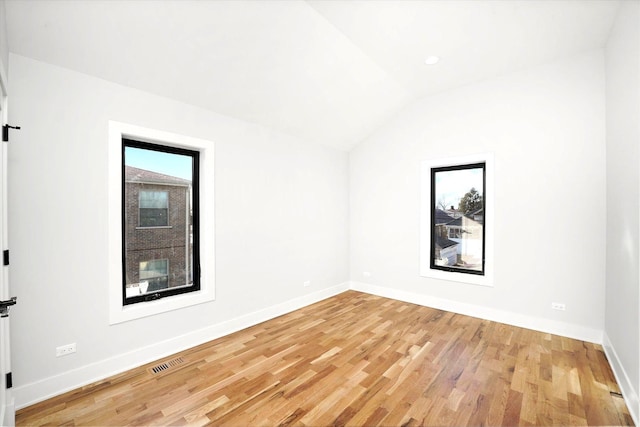 unfurnished room featuring lofted ceiling and light hardwood / wood-style flooring