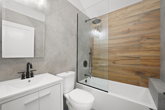 full bathroom featuring vanity, toilet, combined bath / shower with glass door, and tile walls