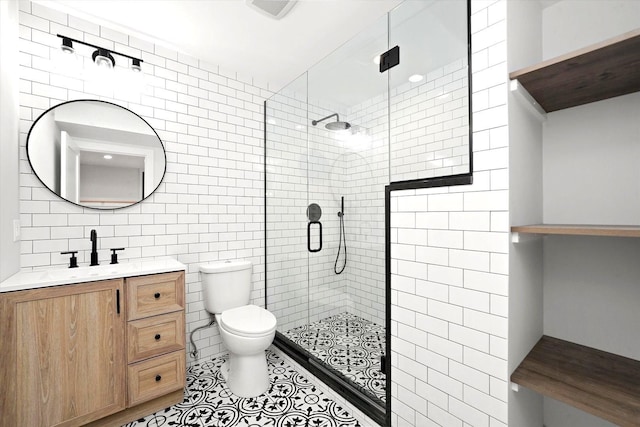 bathroom featuring toilet, a shower with shower door, tile walls, vanity, and tile patterned flooring