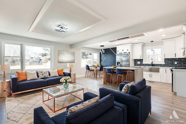 living room featuring a healthy amount of sunlight, sink, and light hardwood / wood-style floors