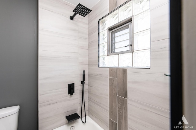 bathroom with tiled shower / bath combo and toilet