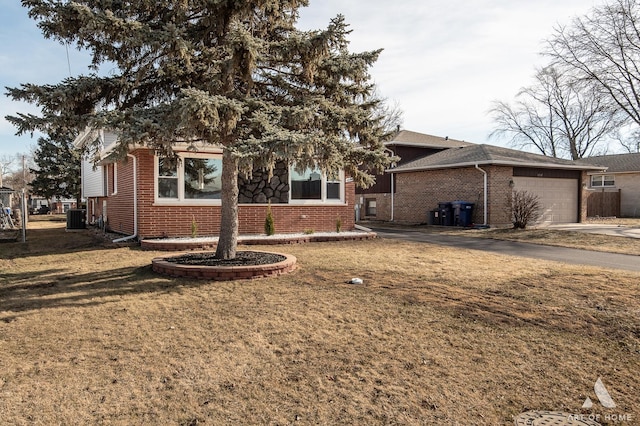 view of front of home featuring a garage, a front yard, and central air condition unit