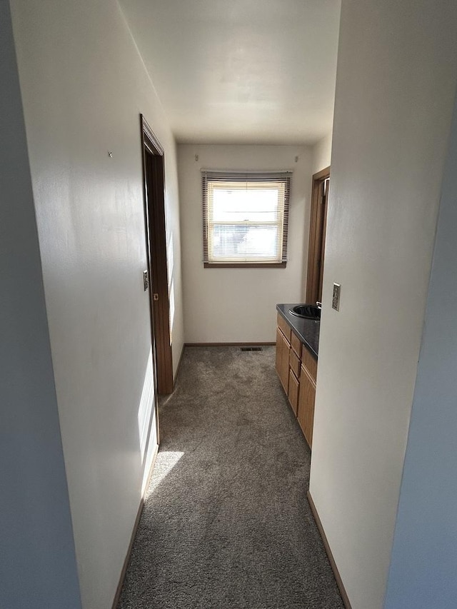 hall with sink and dark carpet