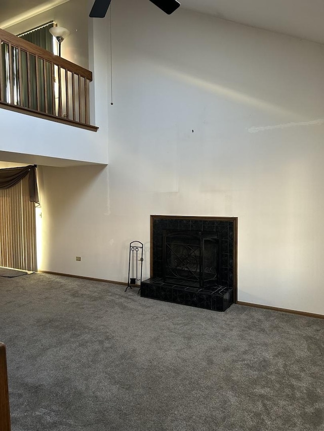 unfurnished living room with a tiled fireplace, high vaulted ceiling, and carpet