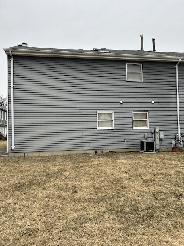 back of property featuring a yard and central AC