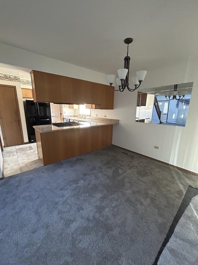 kitchen with black refrigerator, hanging light fixtures, a notable chandelier, kitchen peninsula, and light carpet