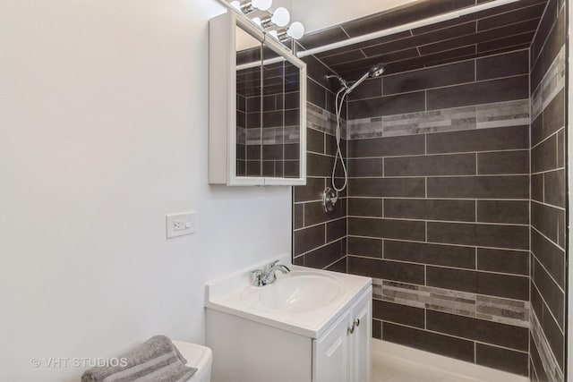 bathroom with vanity, toilet, and a tile shower