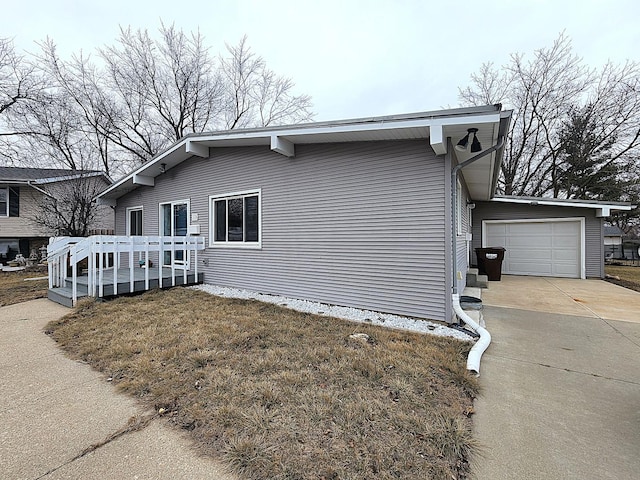 view of property exterior with a garage, a wooden deck, and a lawn