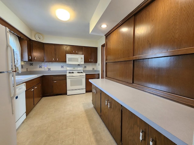 kitchen featuring tasteful backsplash, dark brown cabinetry, and white appliances