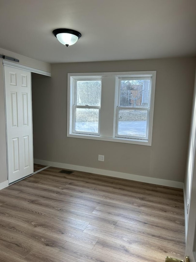 unfurnished bedroom featuring a barn door, a closet, and light wood-type flooring