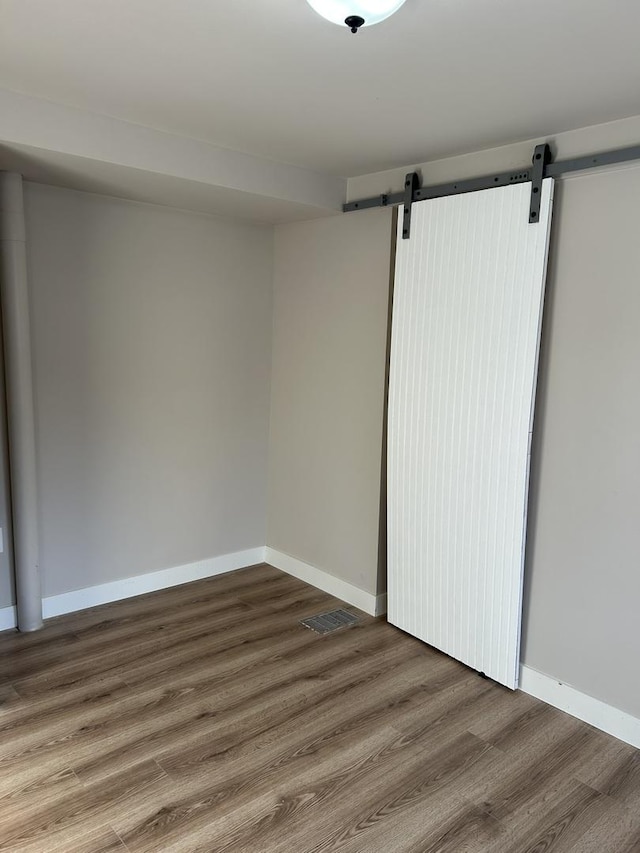 unfurnished room with hardwood / wood-style floors and a barn door