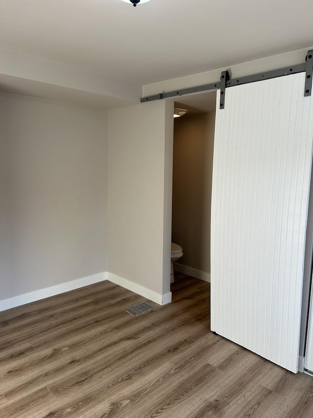 spare room with a barn door and dark wood-type flooring