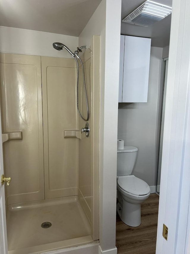 bathroom featuring wood-type flooring, toilet, and a shower